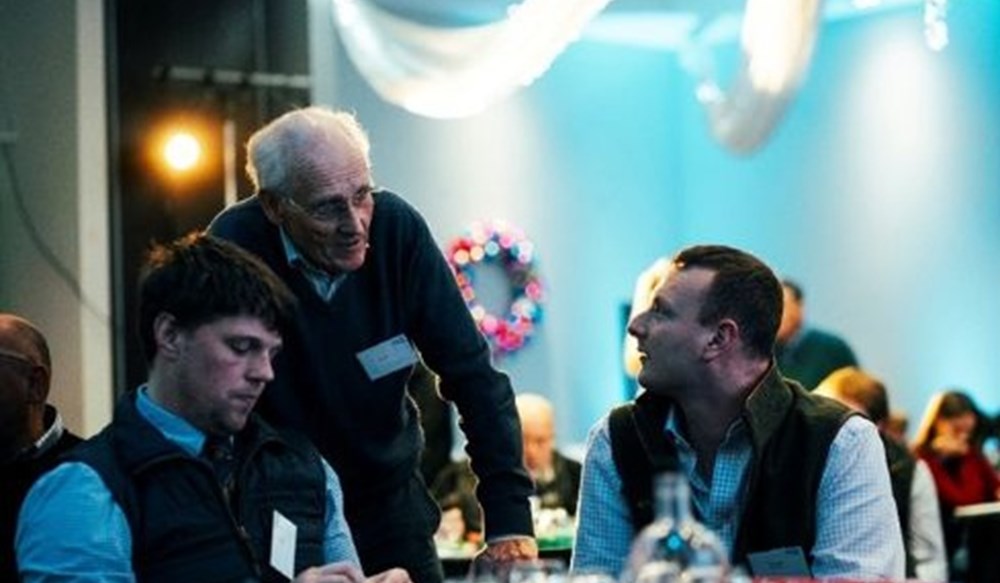 People talking at tables during an indoor event.